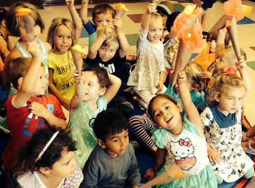 Group of preschool children raising their hands.